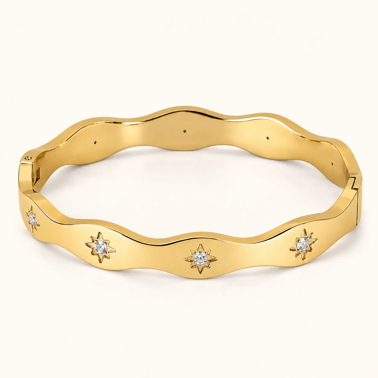 A polished yellow gold bangle bracelet with a wavy outer edge and four small star-shaped diamond accents spaced along the front, shown on a clean off-white background.